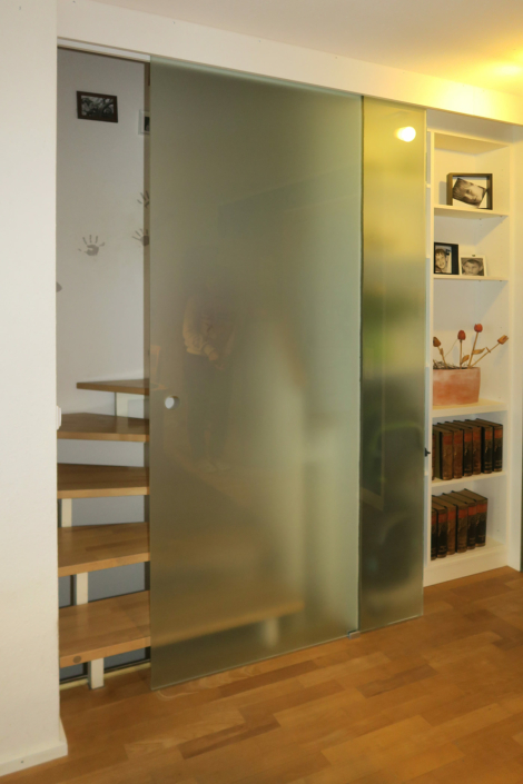 Glasschiebetüren mit Regal vor offener Treppe