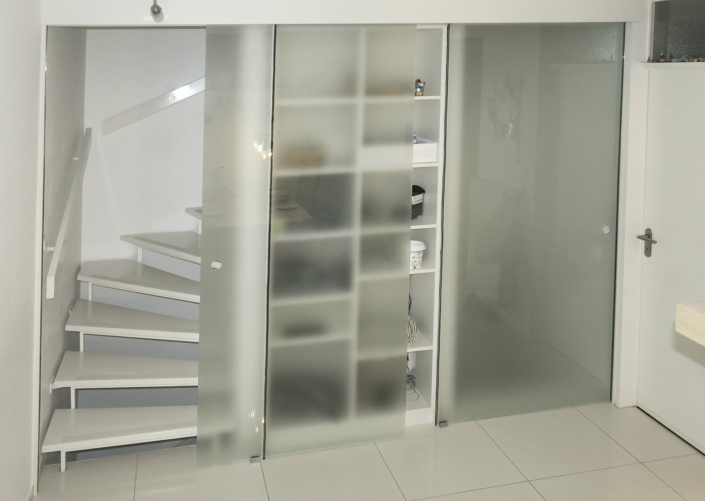 Glasschiebetüren mit Regal vor offener Treppe